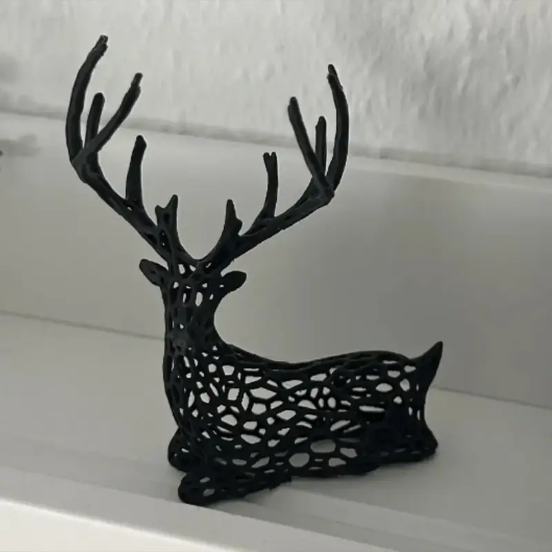 Elegant black 3D-printed reindeer ornament with intricate cut-out design, shown on a wooden surface