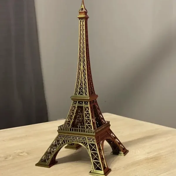 3D printed Eiffel Tower replica displayed on a light-colored wooden table against a plain gray background
