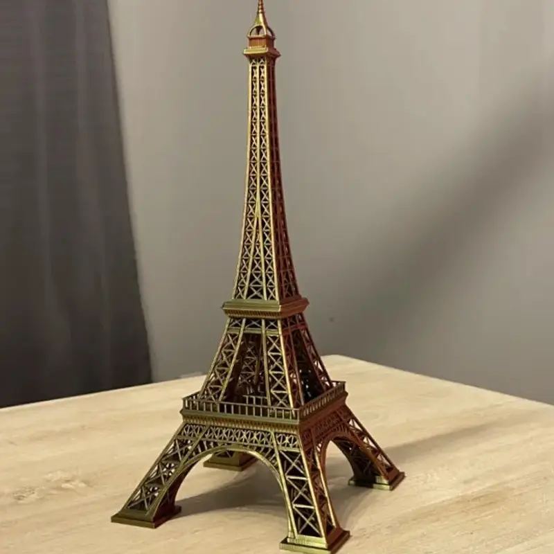 3D printed Eiffel Tower replica displayed on a light-colored wooden table against a plain gray background