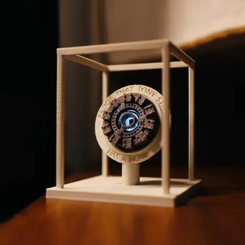 Custom 3D printed Arc Reactor display piece mounted on white stand, showing detailed Marvel design and inscription