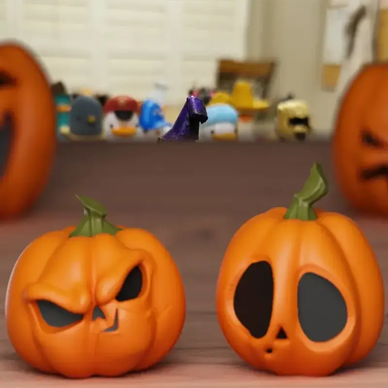 Two custom-carved 3D printed pumpkin ornaments with detailed faces on a wooden surface, showcasing Halloween decor for B2B clients