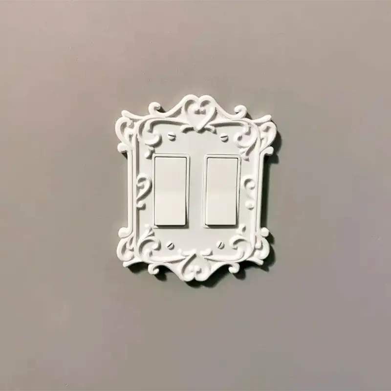 White 3D printed Victorian ornate switch plate with scrollwork and heart detail, mounted on gray wall