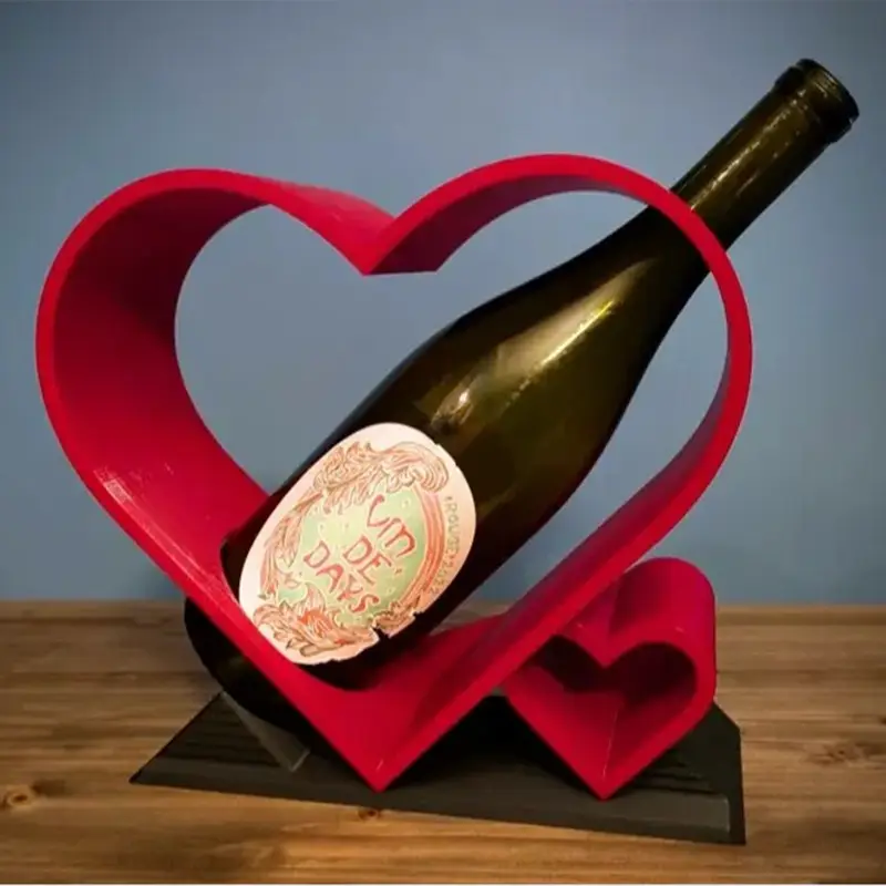 Elegant red heart-themed bottle cradle holding a wine bottle with visible label details on wooden surface