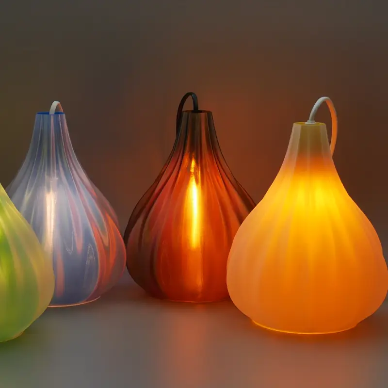 Set of four custom 3D printed light bulb shades in different colors, emitting a warm glow and placed side by side on a surface