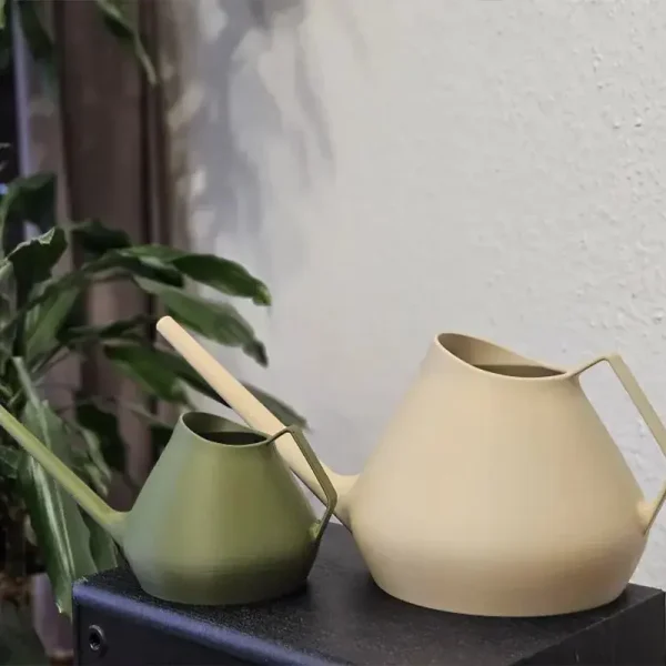 Premium 3D printed watering cans in olive green and sand white colors, showcasing sleek design on dark surface with plant background