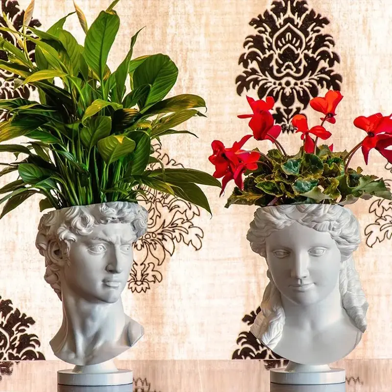 White 3D printed David sculpture planter holding lush green plants against a decorative patterned background