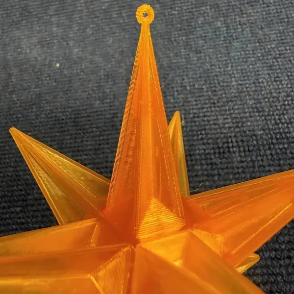 Close-up view of precision 3D printed star tree topper showing sharp geometric edges and translucent orange material
