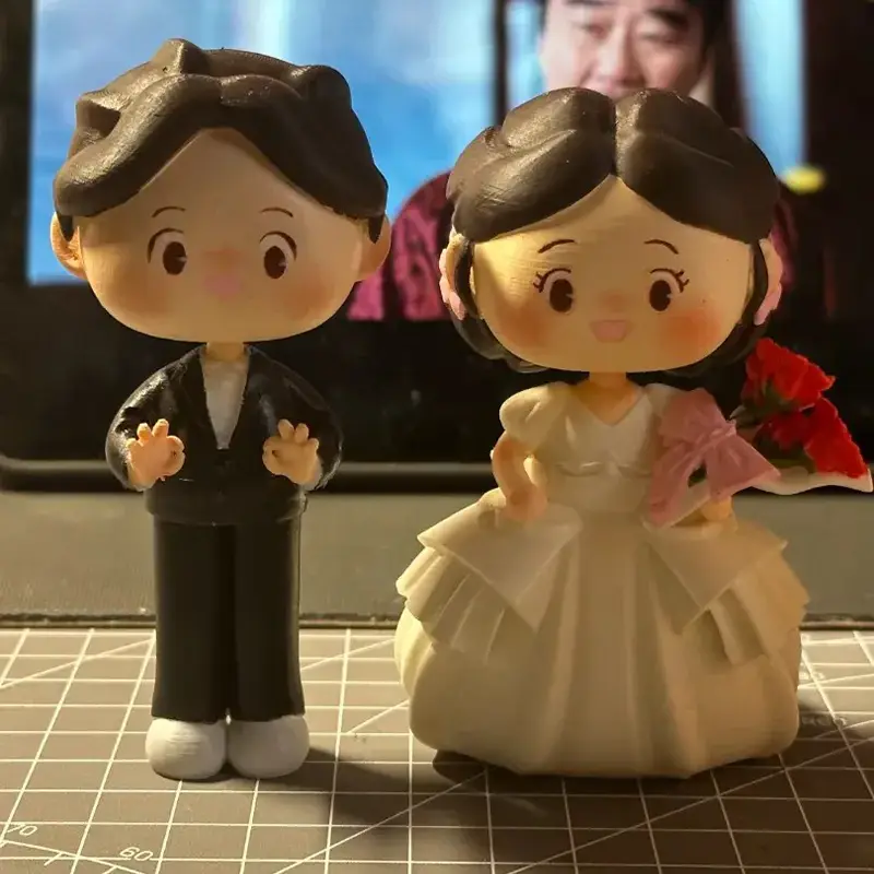 Adorable 3D printed bespoke wedding Q-dolls showing bride and groom in detailed outfits for B2B clients