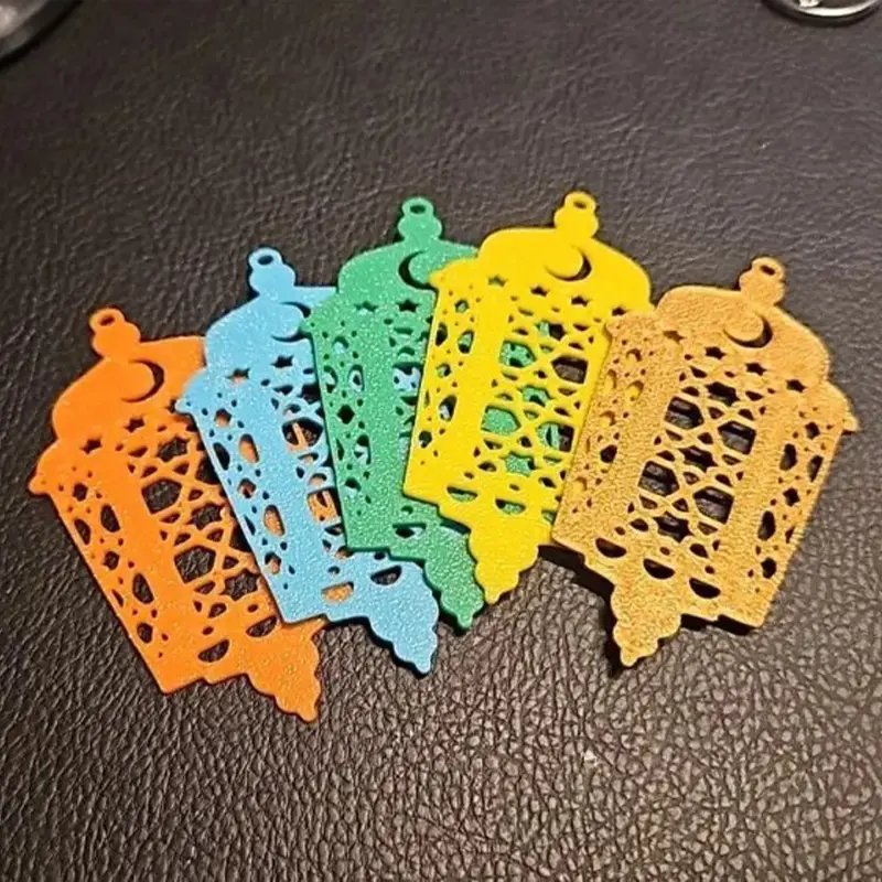 Set of ornate Islamic pendant keychains in orange, blue, green, yellow, and gold colors displayed on dark surface