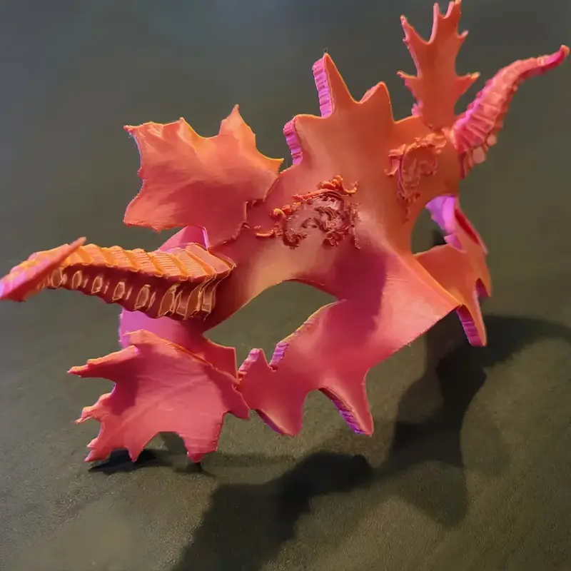 Elegant 3D-printed Halloween ball mask featuring pink and orange floral patterns, displayed on a dark background for B2B clients