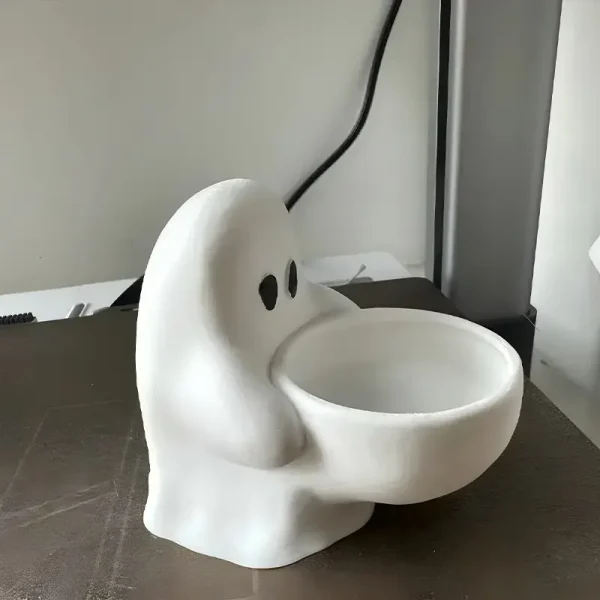 Custom 3D printed ghost candle holder glowing with candlelight against pumpkin and fairy light backdrop for Halloween decor