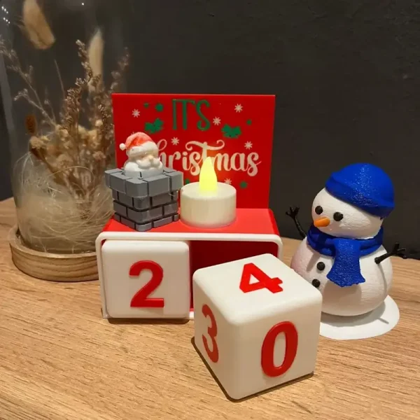 Close-up view of precision 3D printed advent calendar showing Santa detail, warm candle glow, and "it's Christmas" message
