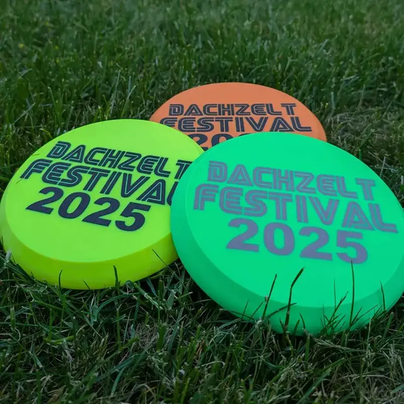 Set of premium 3D printed flying discs showing "DACHZELT FESTIVAL 2025" customization on grass background