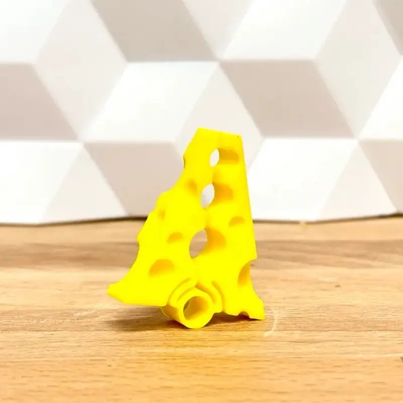 Yellow 3D printed cheese-design bag clip with realistic hole patterns on wooden surface