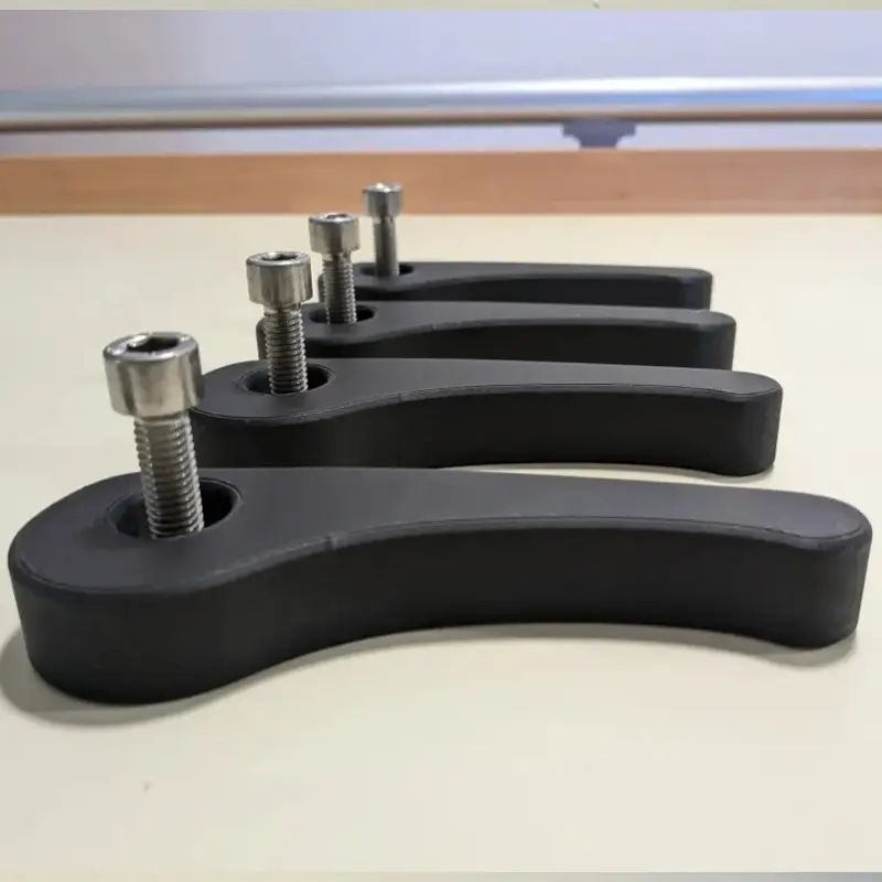 Set of black 3D printed precision workholding solutions with silver screws on neutral background